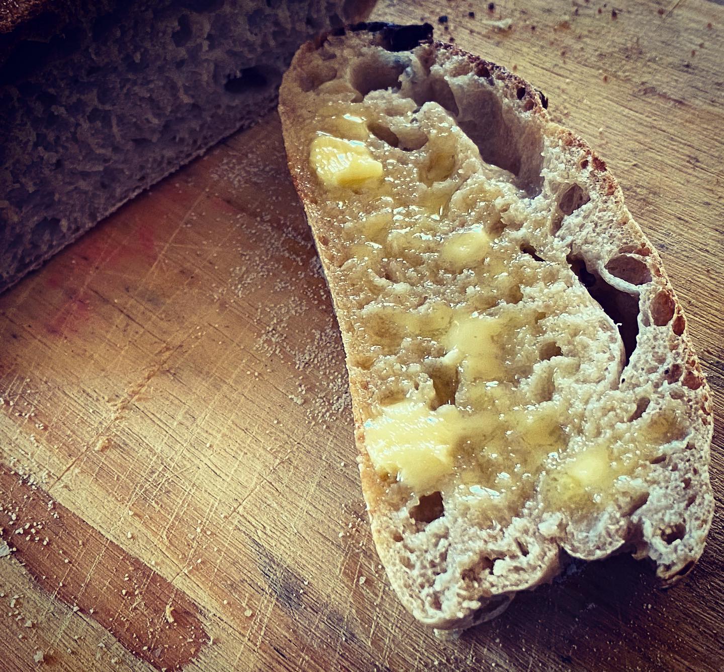 Gebotterde sny suurdeegbrood met oop krummel